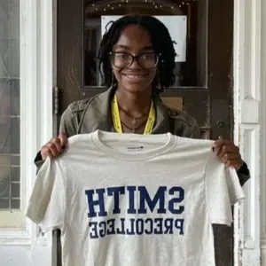 A precollege student holding up a Smith shirt.